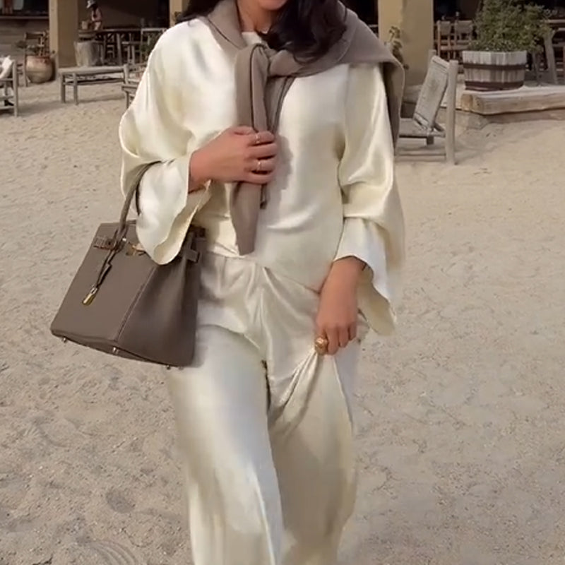 Zīdains un elegants satīna bikšu komplekts ar platu kaklu, garām piedurknēm ar brīvu augšdaļu un elastīgu vidukli.